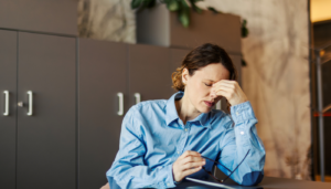 Woman visibly upset, hunched over table.