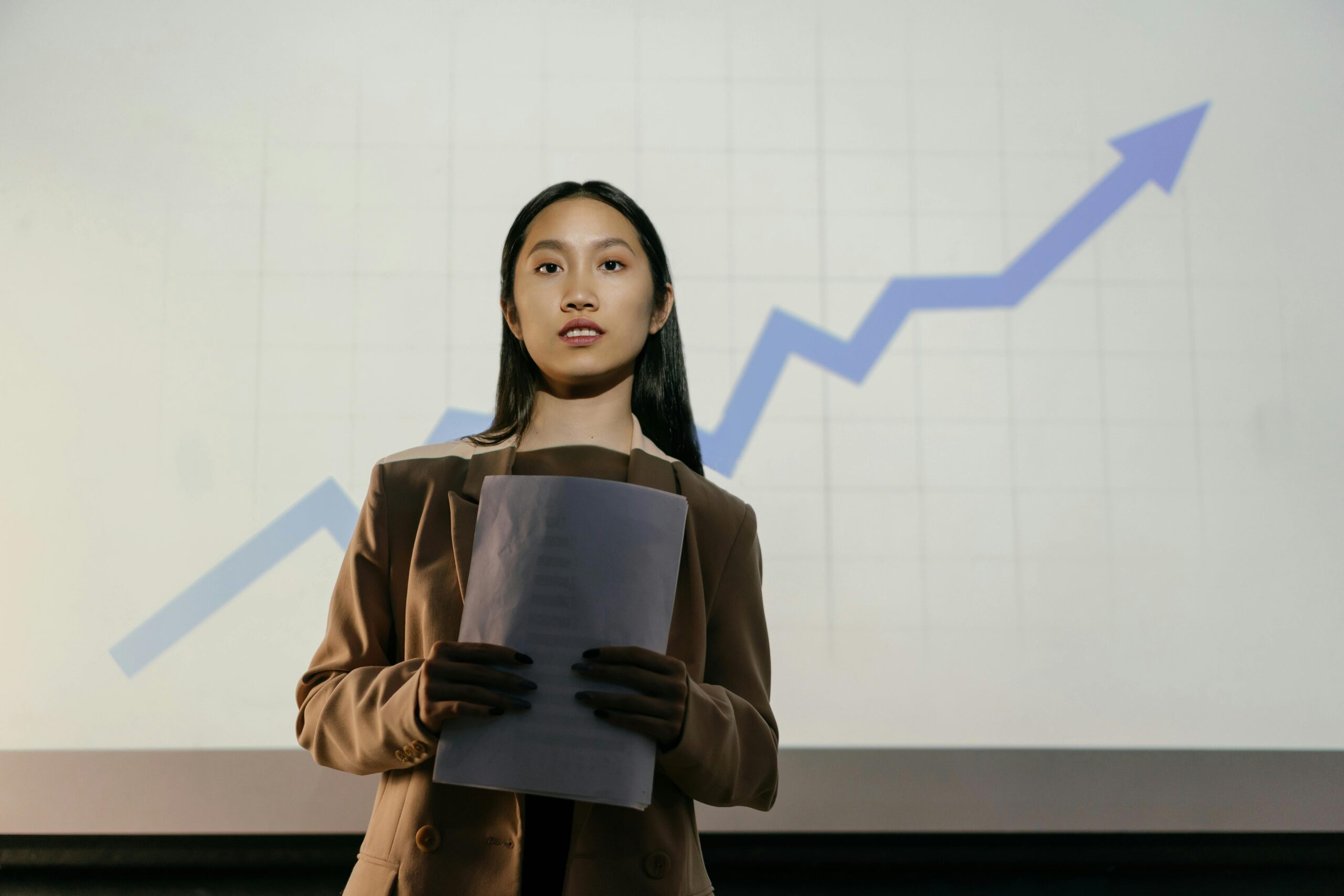Woman standing in front of a graph with an upwards tick in data presentation