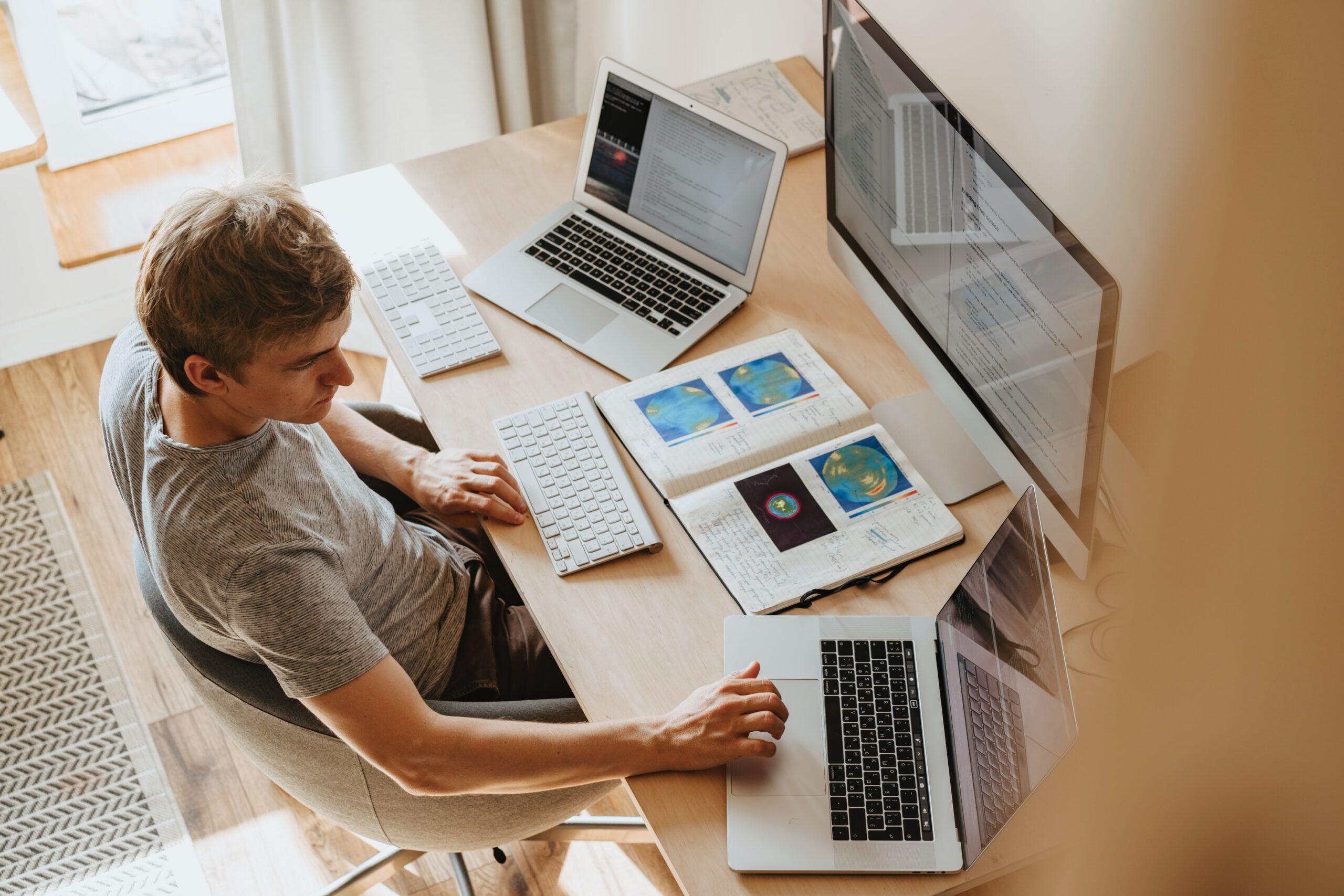 Bird's eye view of man working at home on three computer screens