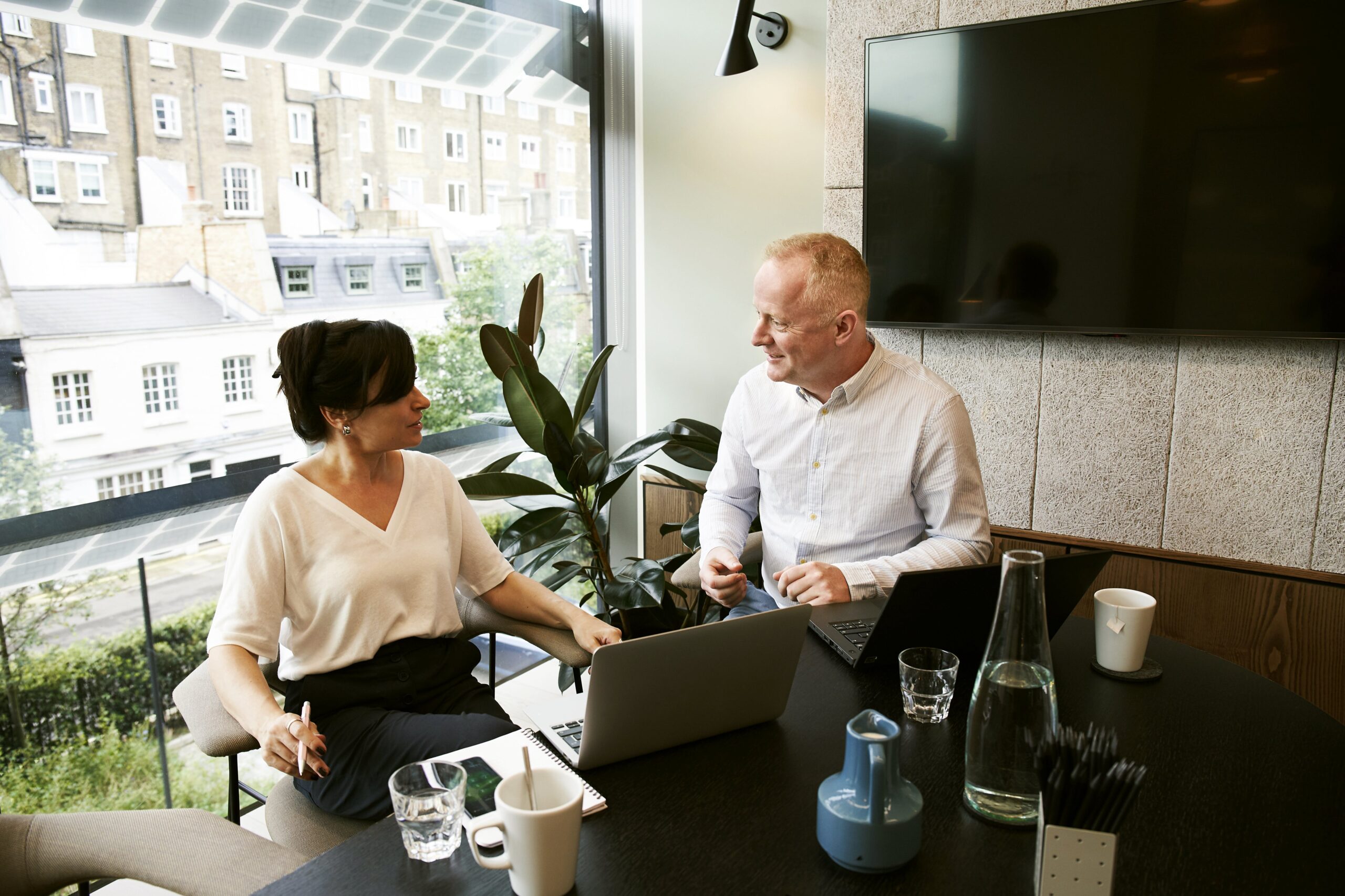 Image of an older man and younger women sitting in front of a laptop in an office