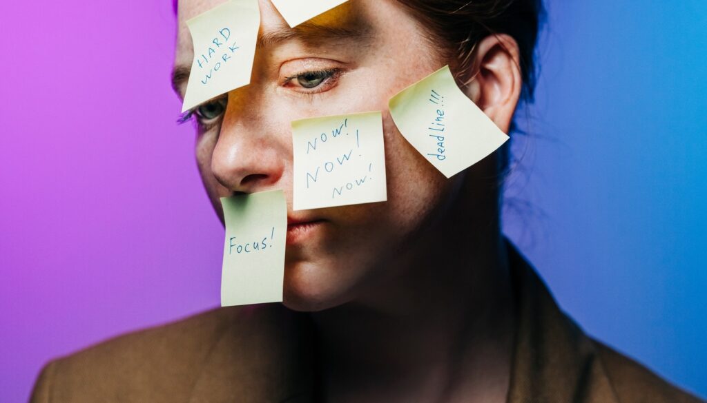 Woman with post-it notes on her face that read 'urgent' 'deadline' 'focus'